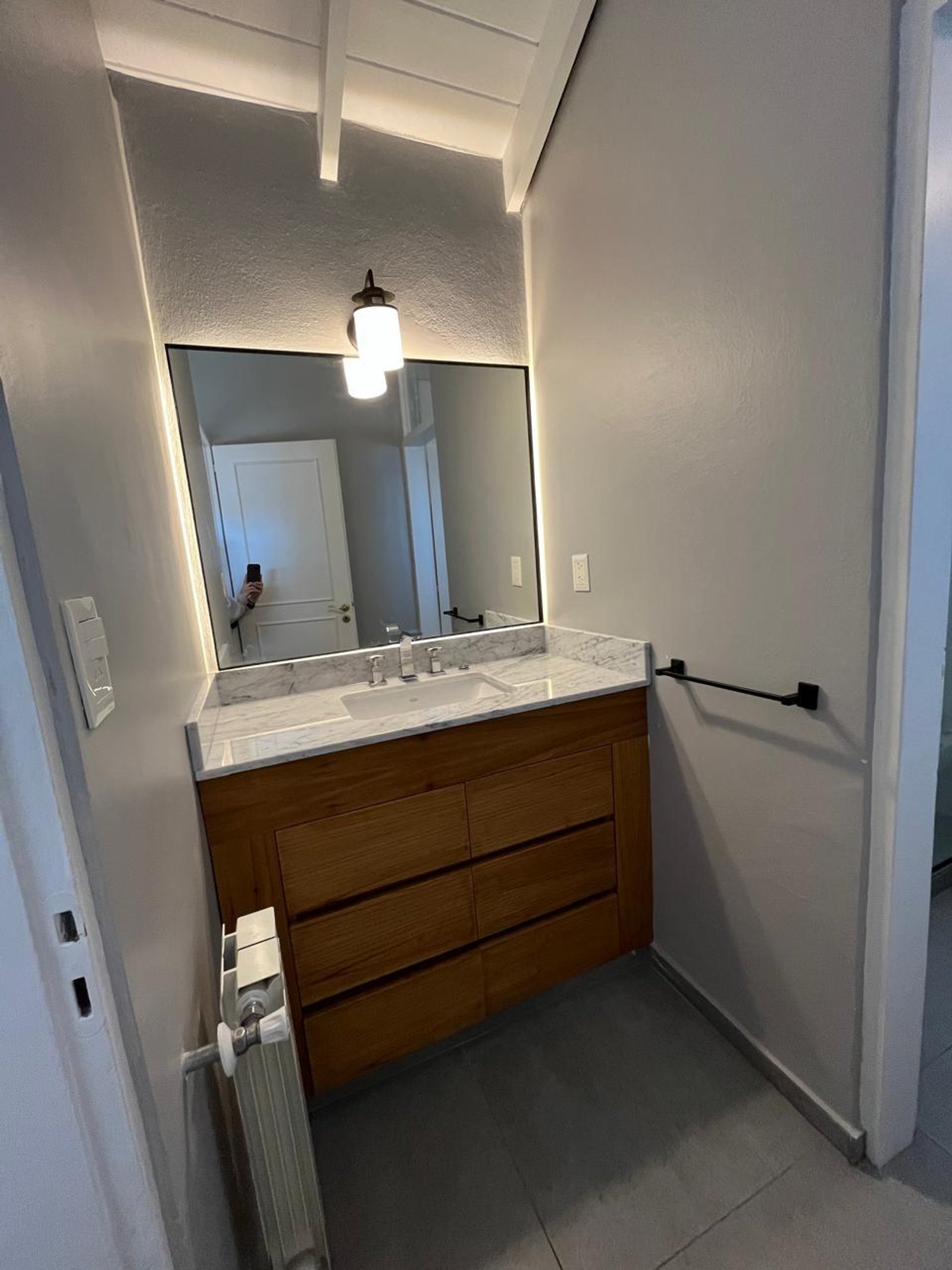 Baño moderno con vanitory de madera y luz indirecta — proyecto Acassuso, por Estudio NET Arquitectura , en Domingo de Acassuso